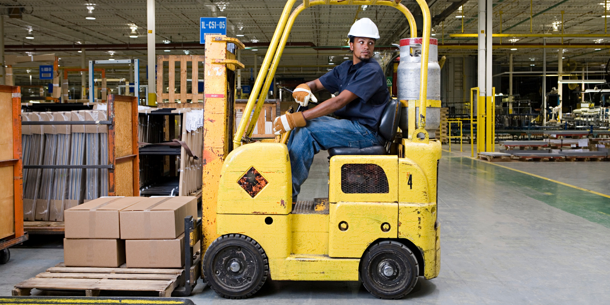 man backing up a forklift in a warehouse