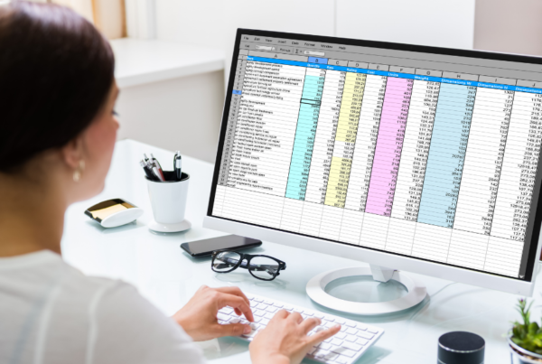 woman sitting at desk looking at spreadsheet on computer